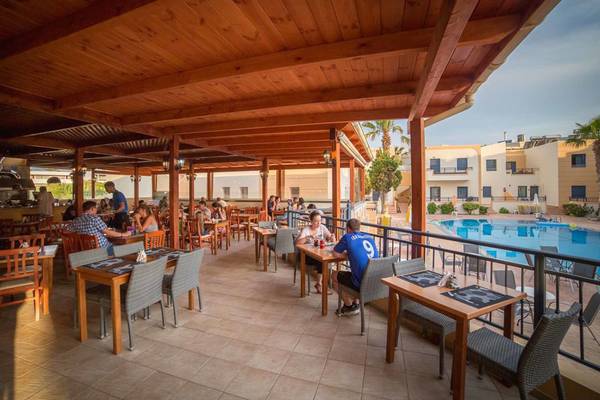 Gäste sitzen an Tischen auf der Terrasse des Blue Aegean Hotel & Suites mit Blick auf den Pool.