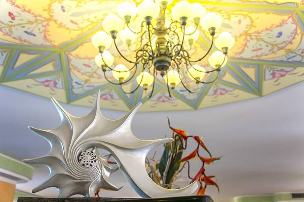 Ein Hotel-Lobby mit einer großen, silbernen Muschelskulptur und einer kunstvollen Deckenlampe.
