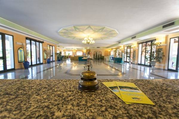 Empfangshalle des Club Hotel Marina Beach mit Gläsern, Pflanzen und Broschüren auf dem Tresen