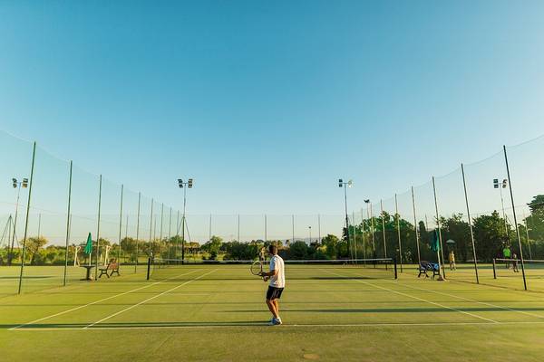 Tennisplatz im Club Hotel Marina Beach mit einem Spieler, der einen Ball schlägt.