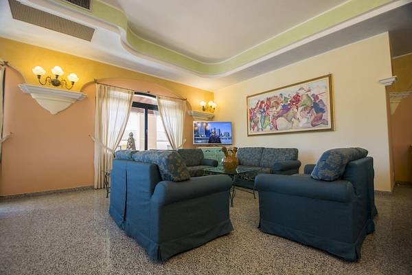 Wohnzimmer im Club Hotel Marina Beach mit blauen Sofas und einem Fernseher.