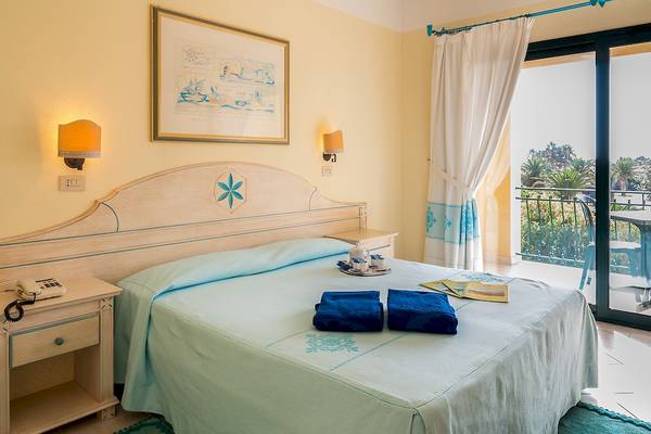 Doppelbett im Club Hotel Marina Beach Zimmer mit Blick auf den Balkon und Außenbereich.