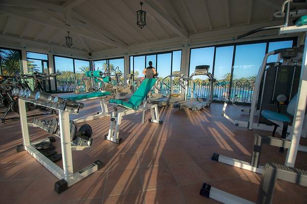 Fitnessstudio im Club Hotel Marina Beach mit Geräten und einem Mann, der auf einem Laufband läuft.