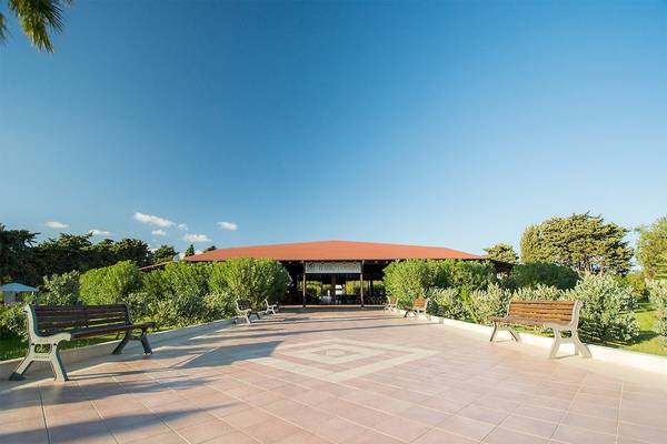 Eingangsbereich des Club Hotel Marina Beach mit Bänken und grünen Büschen