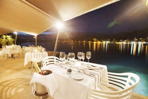 Außenbereich des Croatia Hotels mit Tisch, der zum Meer ausgerichtet ist, bei Nacht