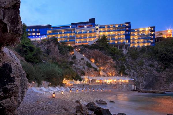 Abendansicht des Croatia Hotels, das auf einem Felsvorsprung mit Blick auf das Meer illuminiert ist.
