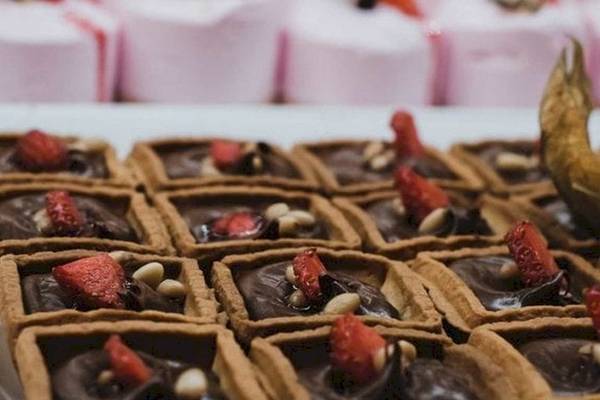 Schokoladentartelette vom AX Odycy Hotel mit Erdbeeren und Nüssen auf einer weißen Platte.