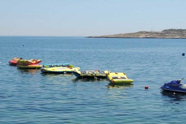 Mehrere Schwimminseln und ein Jetski im Wasser neben dem AX Odycy Hotel.