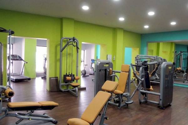 Fitnessraum im AX Odycy Hotel mit grünen Wänden und verschiedenen Trainingsgeräten.