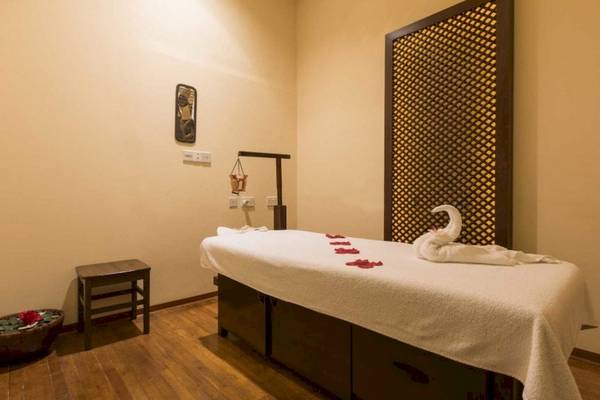 Massagebereich im AX Odycy Hotel mit einem Behandlungstisch, einem Stuhl und einem Blumentopf.