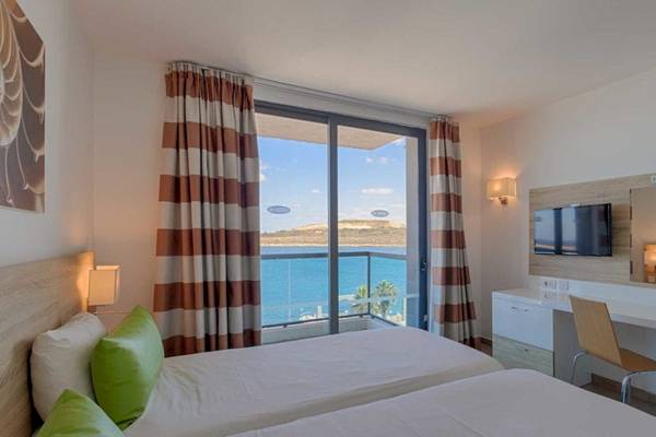 Zimmer im AX Odycy Hotel mit Blick auf das Meer von zwei Betten, einem Schreibtisch und einer Terrasse.