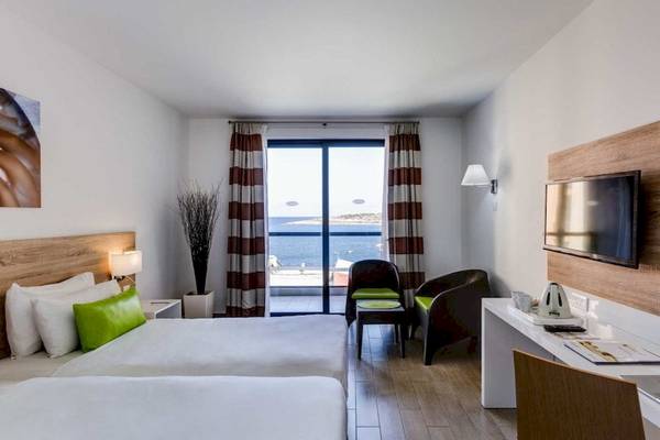 Zimmer im AX Odycy Hotel mit zwei Betten, Meerblick und modernen Einrichtungen.