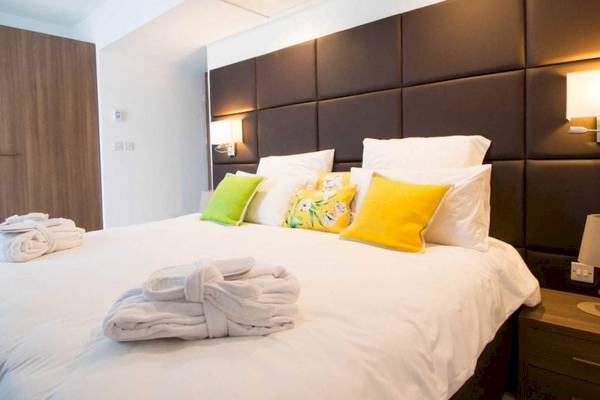 Schlafzimmer im AX Odycy Hotel mit einem großen Bett, mehreren Kissen und Handtüchern.