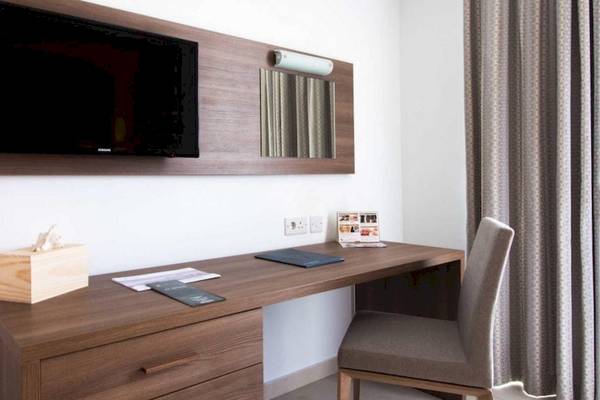 AX Odycy Hotelzimmer mit Schreibtisch, Fernseher und Stuhl.