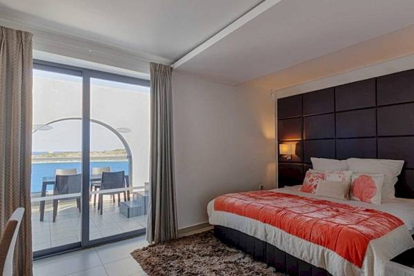 AX Odycy Hotelzimmer mit Meerblick, Bett, Sessel, Tisch und Balkon.