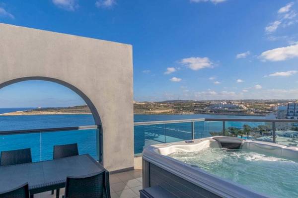Balkon des AX Odycy Hotels mit Whirlpool und Meerblick, Tischen und Stühlen.