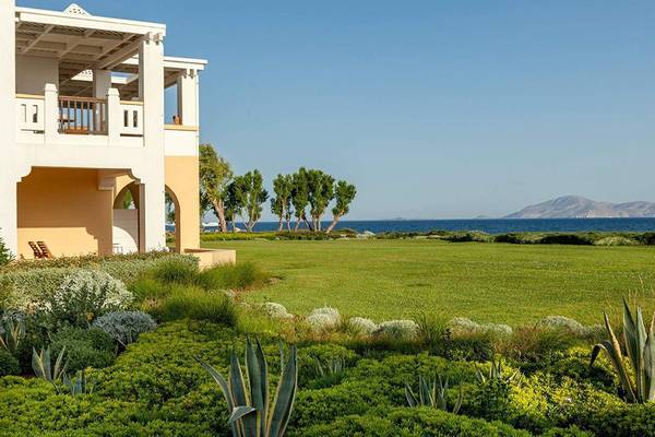 Außenansicht des Neptune Luxury Resort mit einem großen Rasen und Blick auf das Meer.