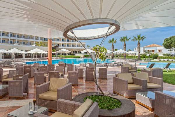 Pool-Lounge-Bereich im Neptune Luxury Resort mit Sonnenschirmen und Liegestühlen.