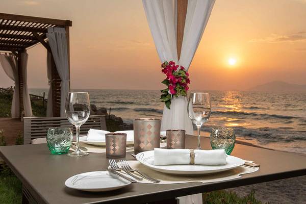 Sonnenuntergang am Meer mit Tisch und Blick auf das Neptune Luxury Resort.