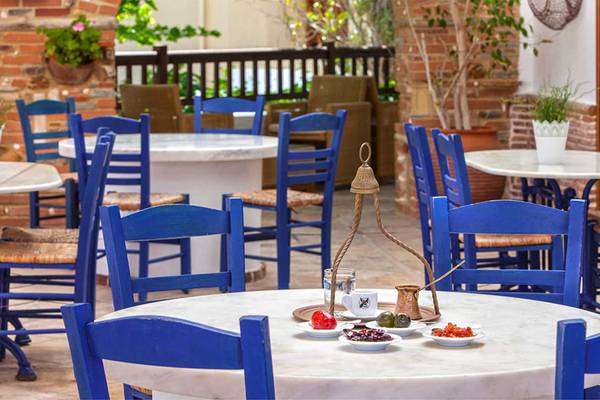 Terrasse des Neptune Luxury Resort mit runden Tischen und blauen Stühlen