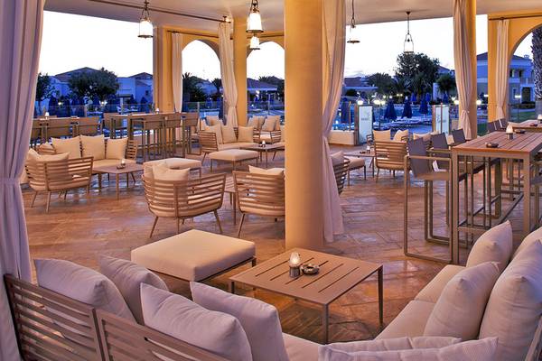 Loungebereich des Neptune Luxury Resorts mit Tischen, Stühlen und Kissen.