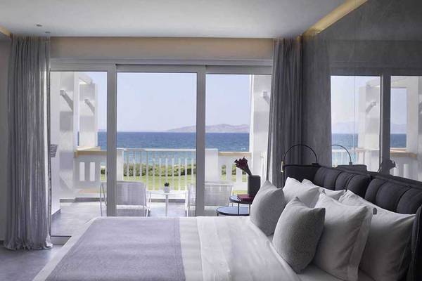 Zimmer im Neptune Luxury Resort mit Blick auf das Meer von einem Balkon.