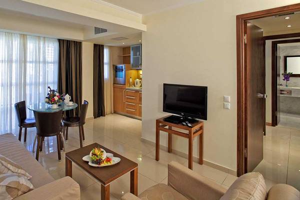 Wohnbereich im Neptune Luxury Resort mit Fernseher, Tisch, Stühlen und Sofa.