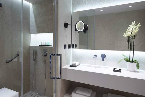 Badezimmer im Neptune Luxury Resort mit Glasdusche, Waschbecken, Spiegel und Blumenvase