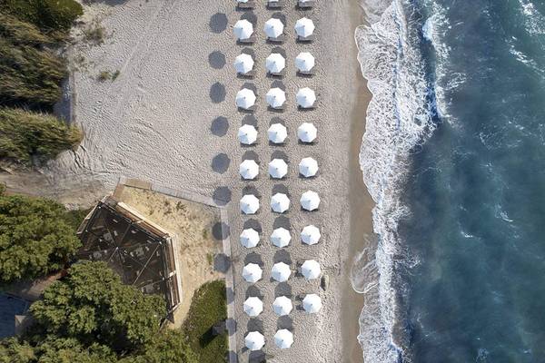 Luftaufnahme des Neptun Luxus Resorts Strands mit weißen Sonnenschirmen und einer kleinen Struktur.
