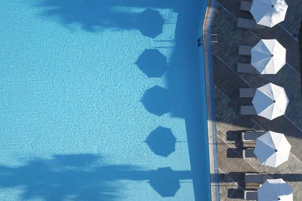 Luftaufnahme des Pools im Neptune Luxury Resort mit Sonnenschirmen und Liegestühlen