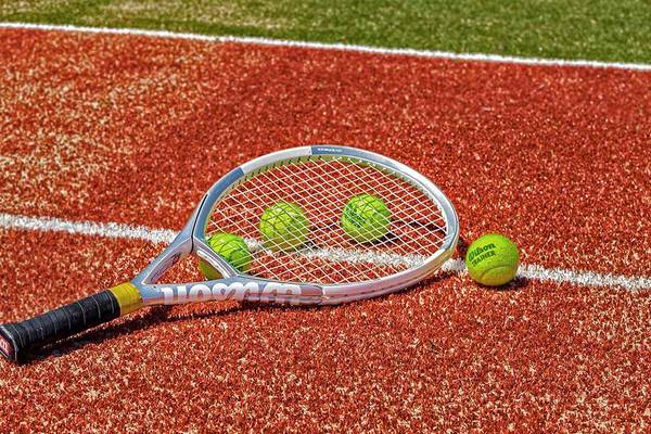 Tennisschläger und Bälle auf rotem Platz.