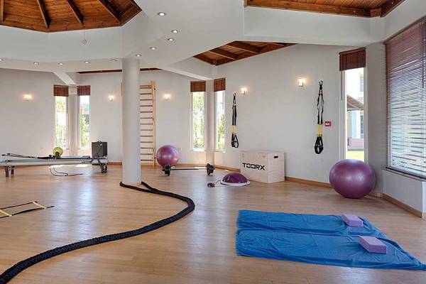 Fitnessbereich im Neptune Luxury Resort mit Trainingsgeräten und Yoga-Matten.