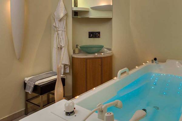 Badezimmer im Neptune Luxury Resort mit einem Whirlpool, umgeben von Lichtern und einem Waschbecken.