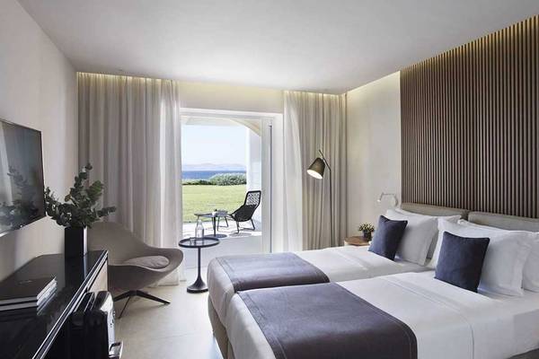 Doppelbettzimmer im Neptune Luxury Resort mit Blick auf den Garten und das Meer.