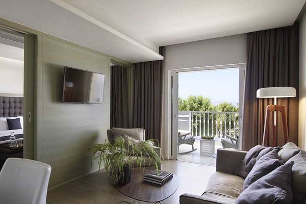 Innenansicht eines Zimmers im Neptune Luxury Resort mit Schlafzimmer, Wohnzimmer, Balkon und modernen Möbeln.