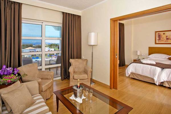 Innenansicht eines Zimmers im Neptune Luxury Resort mit Wohnzimmer und Schlafzimmerbereich.