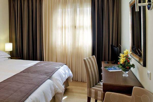 Neptune Luxury Resort Hotelzimmer mit Bett, Schreibtisch und Fenstern.