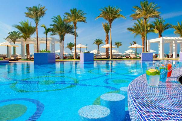 Pool im St. Regis Abu Dhabi mit bunten Mosaiken, Palmen und Sonnenschirmen