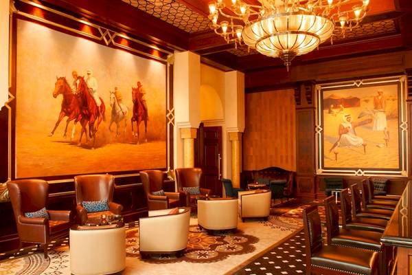 Lobby des St. Regis Abu Dhabi mit Gemälden, Lederstühlen und einem großen Kronleuchter.