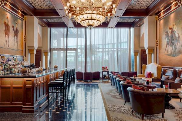 Lobby-Bar im St. Regis Abu Dhabi Hotel mit Bar, Sesseln und Gemälden.