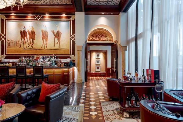 Loungebereich der Bar im St. Regis Abu Dhabi mit Teppich, Lederstühlen und einer großen Wandmalerei von Kamelen.