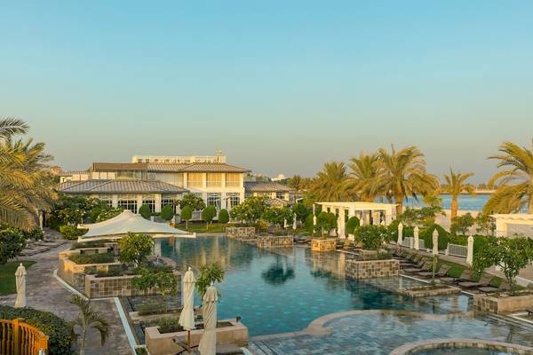 Außenpoolbereich des St. Regis Abu Dhabi Hotels mit Palmen und Sonnenliegen