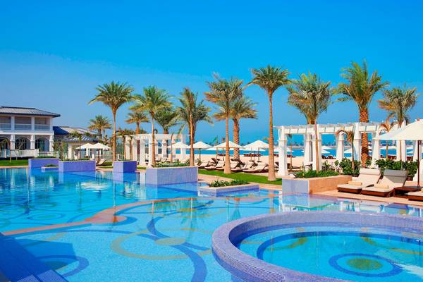 Poolbereich des St. Regis Abu Dhabi Hotels mit Palmen und Sonnenliegen.