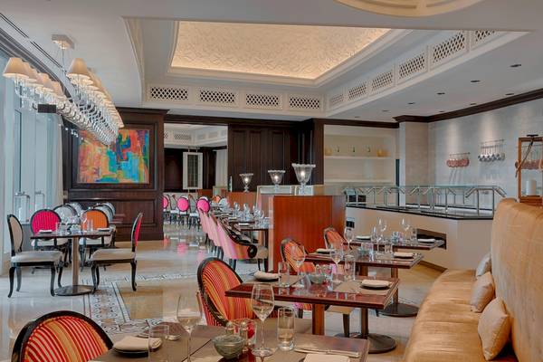 Innenansicht des Restaurants im St. Regis Abu Dhabi mit runden Tischen und Stühlen, gedeckten Tischen und einer Theke im Hintergrund.