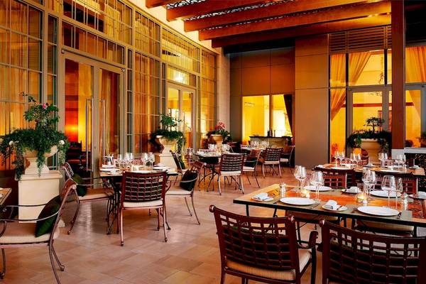Innenansicht des Restaurants im St. Regis Abu Dhabi mit runden Tischen und Stühlen.