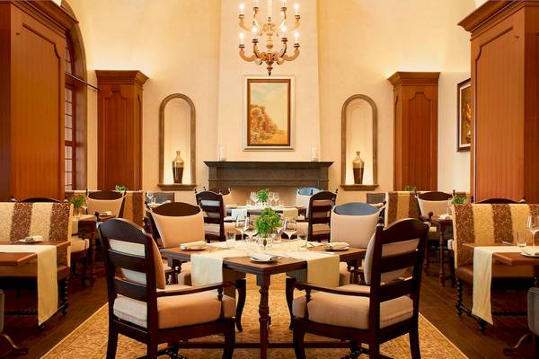 Restaurant-Innenansicht des St. Regis Abu Dhabi mit gerahmten Gemälden und gedeckten Tischen.