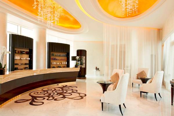 Empfangsbereich des St. Regis Abu Dhabi mit Marmorboden, weißen Sesseln und einer Marmorrezeption.