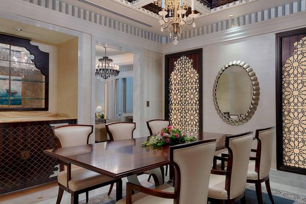 Speisezimmer im St. Regis Abu Dhabi mit elegantem Tisch, Stühlen und Wandverzierungen.