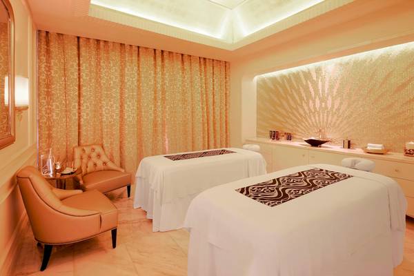 Behandlungsraum im Spa des St. Regis Abu Dhabi mit zwei Massagetischen und eleganten Möbeln.