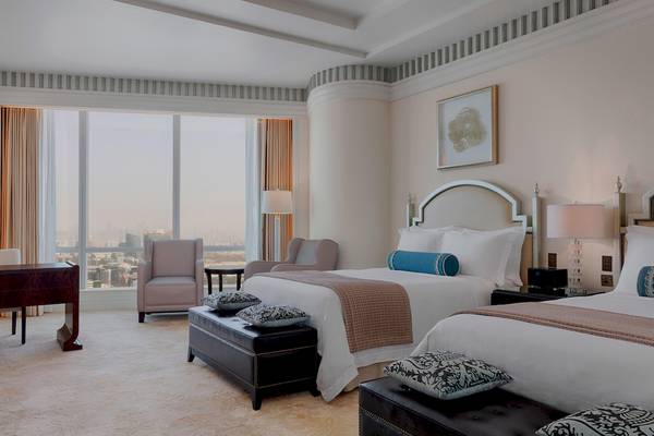 Ein elegantes Hotelzimmer im St. Regis Abu Dhabi mit zwei Betten, Sesseln und Aussicht auf die Stadt.